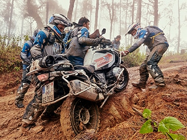 Un groupe de personnes pousse une R 1250 GS Adventure sur une pente.