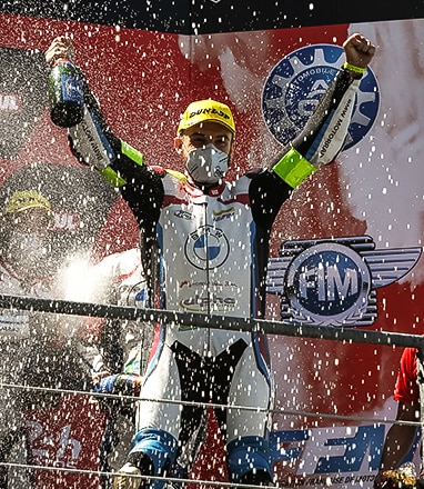 Pilote BMW Motorrad triomphant sur le podium.