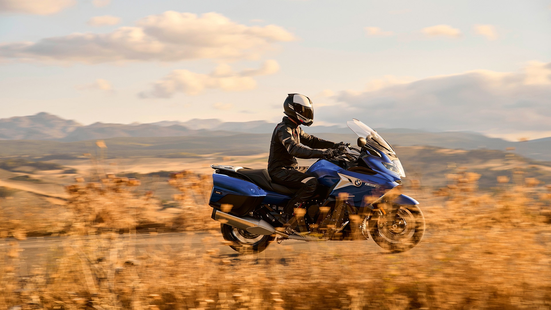 La K 1600 GT Style Sport roule devant un paysage vallonné d’herbes sèches.