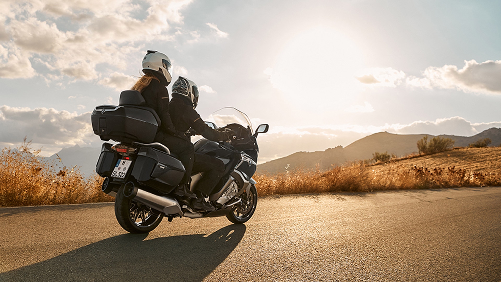 La K 1600 GTL avec son passager devant un paysage vallonné au coucher du soleil.