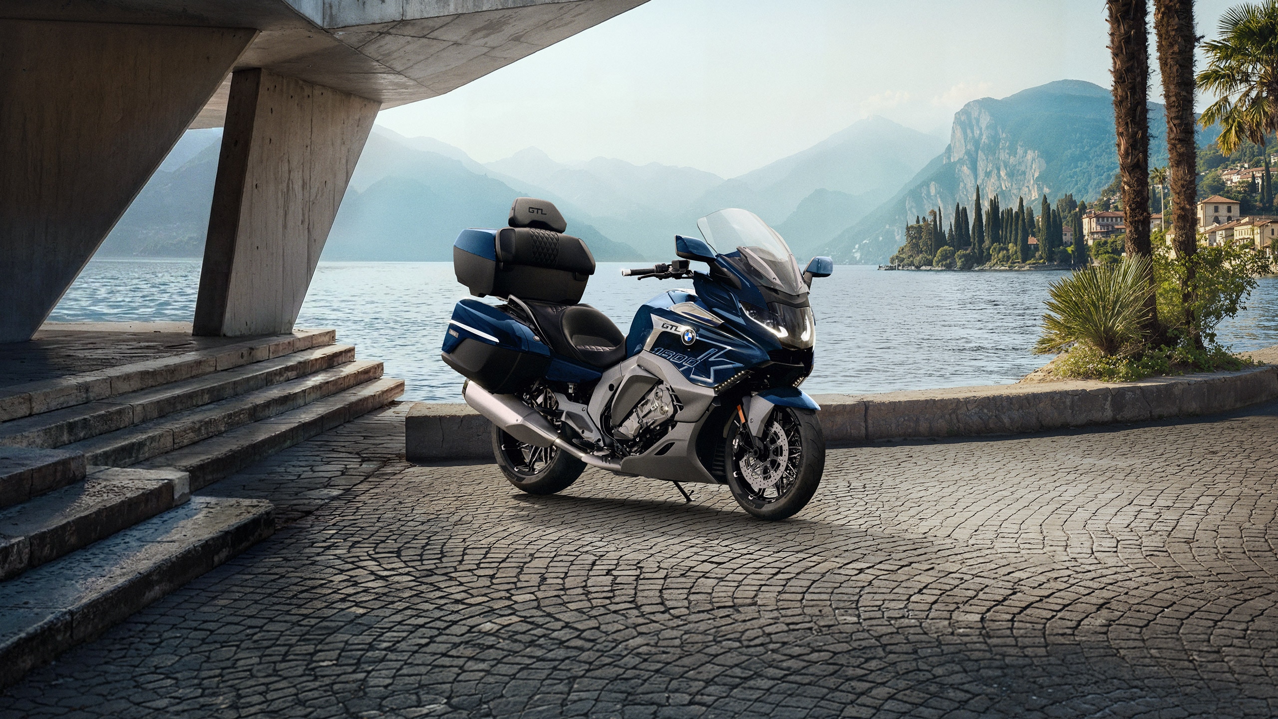 La K 1600 GTL sur un parking avec un fleuve et des montagnes en arrière-plan.